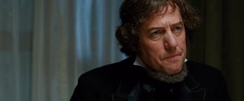 Movie still from “Cloud Atlas” (2012), directed by Lilly Wachowski – A person wearing a suit and tie; Close Up shot, Low angle