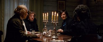 Movie still from “Cloud Atlas” (2012), directed by Lilly Wachowski – A group of men sitting at a dinner table with lit candles; Medium shot, Over the shoulder angle