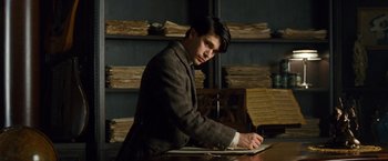 Movie still from “Cloud Atlas” (2012), directed by Lilly Wachowski – A man sitting at a table writing on a piece of paper; Medium shot, Low angle