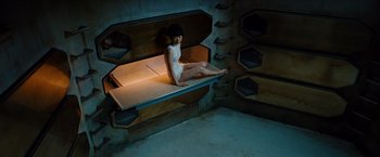 Movie still from “Cloud Atlas” (2012), directed by Lilly Wachowski – A woman sitting on top of a bench in a room; Wide shot, High angle