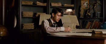 Movie still from “Cloud Atlas” (2012), directed by Lilly Wachowski – A man sitting at a table writing on a piece of paper; Medium shot, Low angle