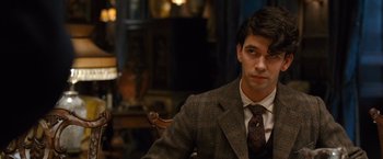 Movie still from “Cloud Atlas” (2012), directed by Lilly Wachowski – A man in a suit and tie sitting in a chair; Close Up shot, Over the shoulder angle