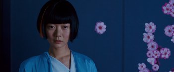 Movie still from “Cloud Atlas” (2012), directed by Lilly Wachowski – A young woman in a blue robe stands in front of a flower; Close Up shot, Over the shoulder angle