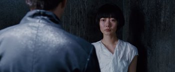 A young asian woman standing next to a man in front of a wall