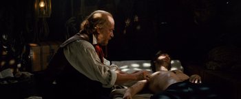 Movie still from “Cloud Atlas” (2012), directed by Lilly Wachowski – An old man with long hair and a beard is holding a man's arm; Medium shot, Over the shoulder angle
