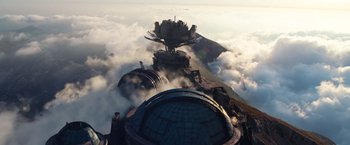 Movie still from “Cloud Atlas” (2012), directed by Lilly Wachowski – An aerial view of a building with a flower on top of it; Extreme Wide shot, Low angle
