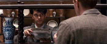 Movie still from “Cloud Atlas” (2012), directed by Lilly Wachowski – A man in a suit holding plates in front of a mirror; Medium shot, Over the shoulder angle