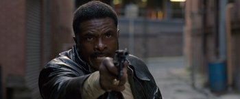 Movie still from “Cloud Atlas” (2012), directed by Lilly Wachowski – A man with a gun pointing at the camera; Close Up shot, Low angle