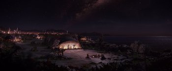 Movie still from “Cloud Atlas” (2012), directed by Lilly Wachowski – People are sitting around a tent on the beach at night; Extreme Wide shot, High angle