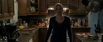 Movie still from “Clown” (2014), directed by Jon Watts – A woman standing in a kitchen looking down at the floor; Medium shot, Over the shoulder angle