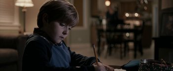 A young boy is writing with a pencil