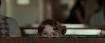 Movie still from “Clown” (2014), directed by Jon Watts – A little girl hiding behind a wooden table; Close Up shot, Over the shoulder angle