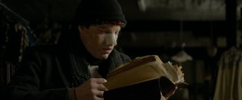 Movie still from “Clown” (2014), directed by Jon Watts – A young man with bandages on his face looking at a book; Close Up shot, Low angle