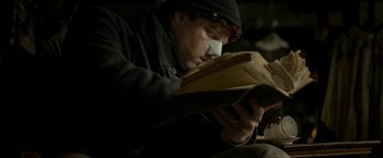 Movie still from “Clown” (2014), directed by Jon Watts – A man reading a book while sitting on a couch; Close Up shot, Low angle