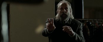 Movie still from “Clown” (2014), directed by Jon Watts – An older man with a beard is giving the peace sign; Medium shot, Over the shoulder angle