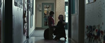 A woman and a boy are walking down a hallway