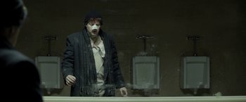 Movie still from “Clown” (2014), directed by Jon Watts – A man with a clown mask standing in front of a wall; Medium shot, Low angle