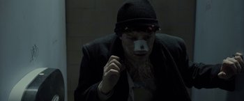 Movie still from “Clown” (2014), directed by Jon Watts – A man in a black jacket and a black hat is looking down; Close Up shot, Low angle