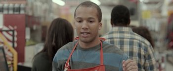 Movie still from “Clown” (2014), directed by Jon Watts – A man in an apron is standing in front of a group of people; Medium shot, Over the shoulder angle