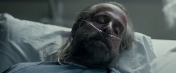 Movie still from “Clown” (2014), directed by Jon Watts – A man with a beard is laying in a hospital bed; Close Up shot, Overhead angle