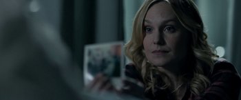 Movie still from “Clown” (2014), directed by Jon Watts – A woman looking at a picture in a dark room; Close Up shot, Over the shoulder angle