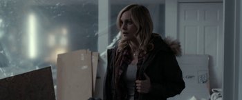 Movie still from “Clown” (2014), directed by Jon Watts – A woman in a hooded jacket standing next to a window; Medium shot, Over the shoulder angle