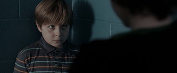 Movie still from “Clown” (2014), directed by Jon Watts – A young boy looking at the camera in front of a wall; Close Up shot, Over the shoulder angle