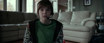 Movie still from “Clown” (2014), directed by Jon Watts – A young boy wearing a headset in a living room; Close Up shot, Over the shoulder angle