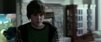 Movie still from “Clown” (2014), directed by Jon Watts – A young boy in a green t - shirt is looking at the camera; Close Up shot, Over the shoulder angle
