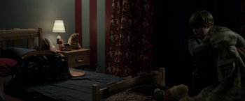 Movie still from “Clown” (2014), directed by Jon Watts – A teddy bear sitting on a bed next to a window; Wide shot, High angle