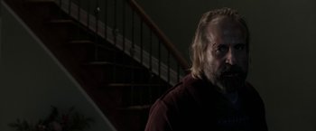 Movie still from “Clown” (2014), directed by Jon Watts – A man standing in front of a stair case; Medium shot, Over the shoulder angle