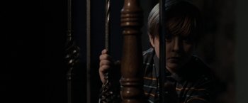 Movie still from “Clown” (2014), directed by Jon Watts – A young boy is looking through the bars of a cage; Medium shot, High angle