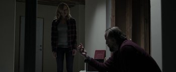 Movie still from “Clown” (2014), directed by Jon Watts – A woman standing next to an older man in front of a table; Medium shot, Over the shoulder angle