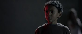 Movie still from “Clown” (2014), directed by Jon Watts – A young boy is standing in a dark room; Close Up shot, Low angle