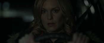 Movie still from “Clown” (2014), directed by Jon Watts – A woman with blonde hair is holding a steering wheel in the dark; Close Up shot, Over the shoulder angle