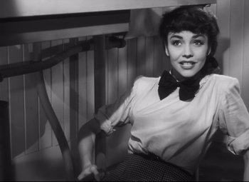 Movie still from “Cluny Brown” (1946), directed by Ernst Lubitsch – A woman sitting on top of a chair wearing a bow tie; Medium shot, Low angle