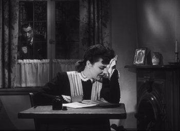 Movie still from “Cluny Brown” (1946), directed by Ernst Lubitsch – A woman sitting at a table with a pen and paper; Medium shot, High angle