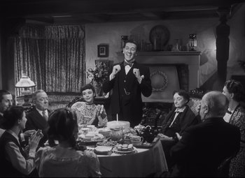 Movie still from “Cluny Brown” (1946), directed by Ernst Lubitsch – An old photo of a group of people sitting at a dinner table; Medium shot, High angle