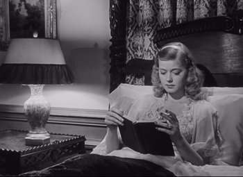 Movie still from “Cluny Brown” (1946), directed by Ernst Lubitsch – A woman sitting on a bed looking at a book; Medium shot, Low angle