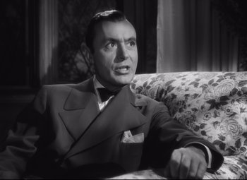 Movie still from “Cluny Brown” (1946), directed by Ernst Lubitsch – A man sitting on a couch wearing a suit and tie; Close Up shot, Low angle