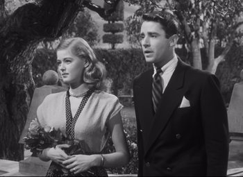 Movie still from “Cluny Brown” (1946), directed by Ernst Lubitsch – A man and a woman standing next to each other holding flowers; Medium shot, Low angle