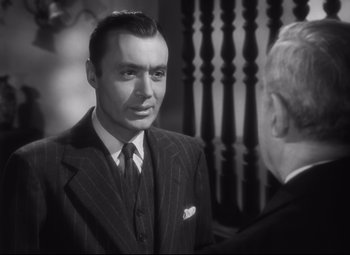 Movie still from “Cluny Brown” (1946), directed by Ernst Lubitsch – A man wearing a suit and tie talking to another man; Close Up shot, Over the shoulder angle