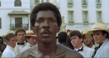 Movie still from “Cobra Verde” (1987), directed by Werner Herzog – A person wearing a hat; Close Up shot, Low angle