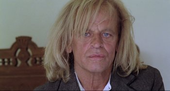 Movie still from “Cobra Verde” (1987), directed by Werner Herzog – A person with long hair; Close Up shot, Low angle