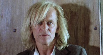 Movie still from “Cobra Verde” (1987), directed by Werner Herzog – A person with long hair; Close Up shot, Low angle