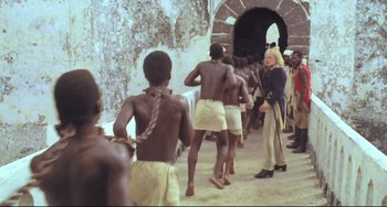 Movie still from “Cobra Verde” (1987), directed by Werner Herzog – A group of people are lined up in a tunnel; Wide shot, High angle