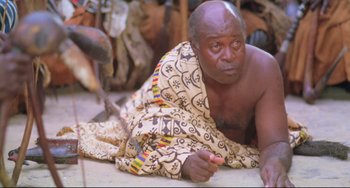 Movie still from “Cobra Verde” (1987), directed by Werner Herzog – An older man is laying on the ground; Close Up shot, High angle