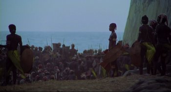 Movie still from “Cobra Verde” (1987), directed by Werner Herzog – A man standing in front of a crowd of people; Extreme Wide shot, High angle