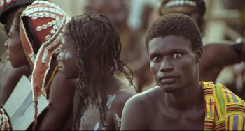 Movie still from “Cobra Verde” (1987), directed by Werner Herzog – A group of people that are standing in the dirt; Close Up shot, High angle