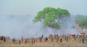 Movie still from “Cobra Verde” (1987), directed by Werner Herzog – A group of people standing in a field near a tree; Extreme Wide shot, High angle